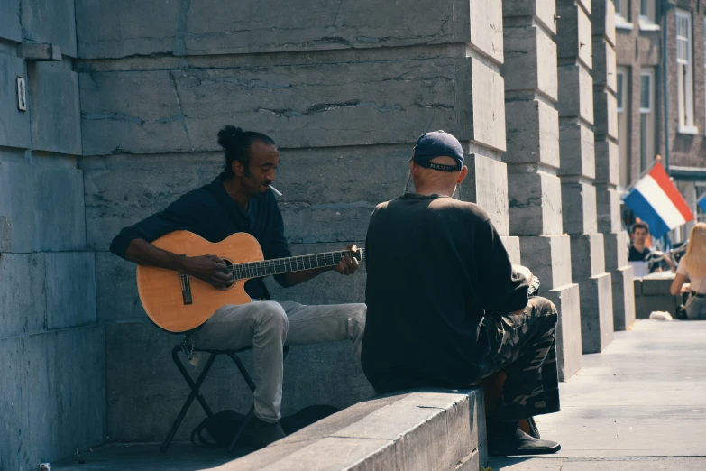 two men sitting on steps playing guitars and other things