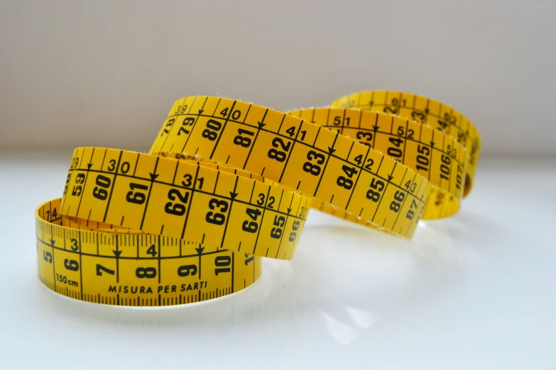 three yellow measuring tapes lying on a table