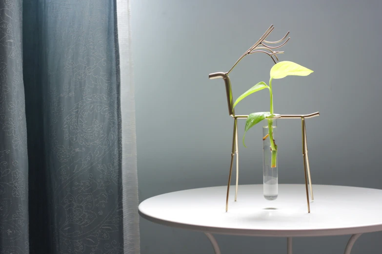 a table with a white table cloth a vase with some green plants in it and the other side of the glass