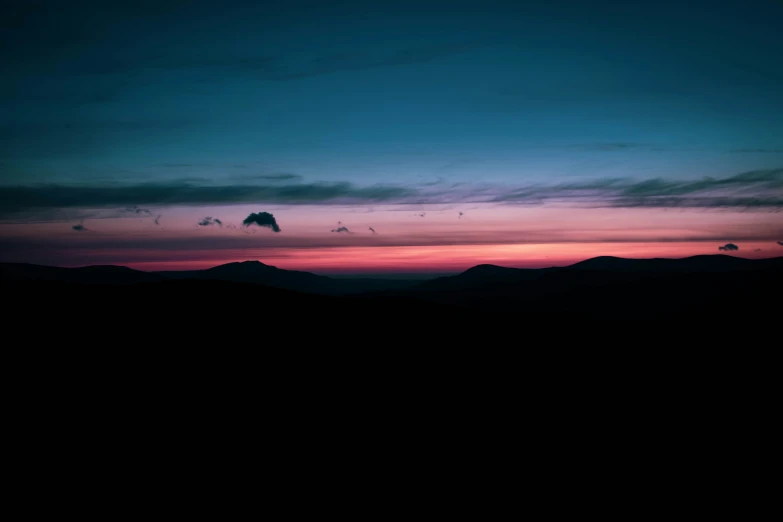 silhouettes of hills at sunset and clouds in the sky