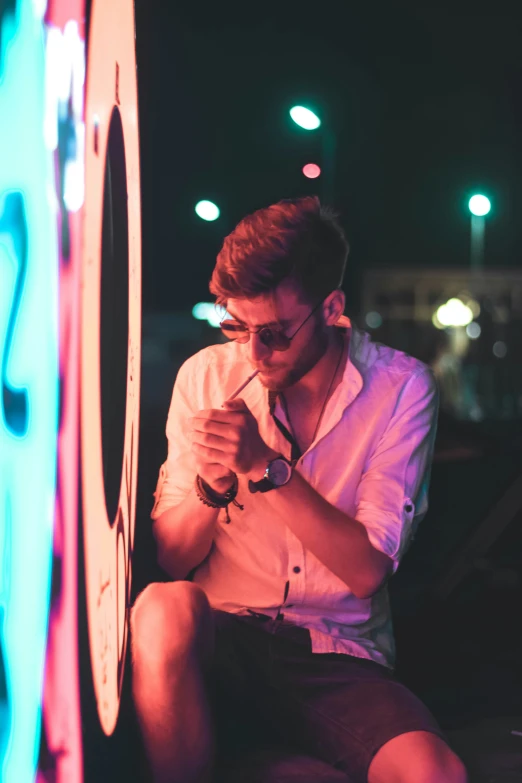 a man with glasses and  is sitting next to a wall