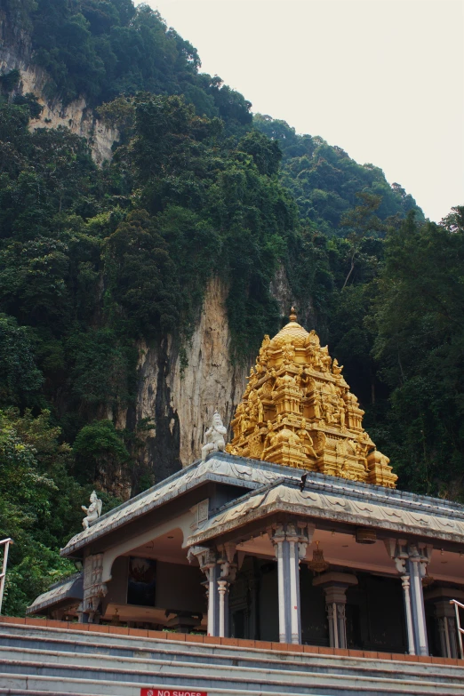 golden temple on the top of a hill with a cliff behind it