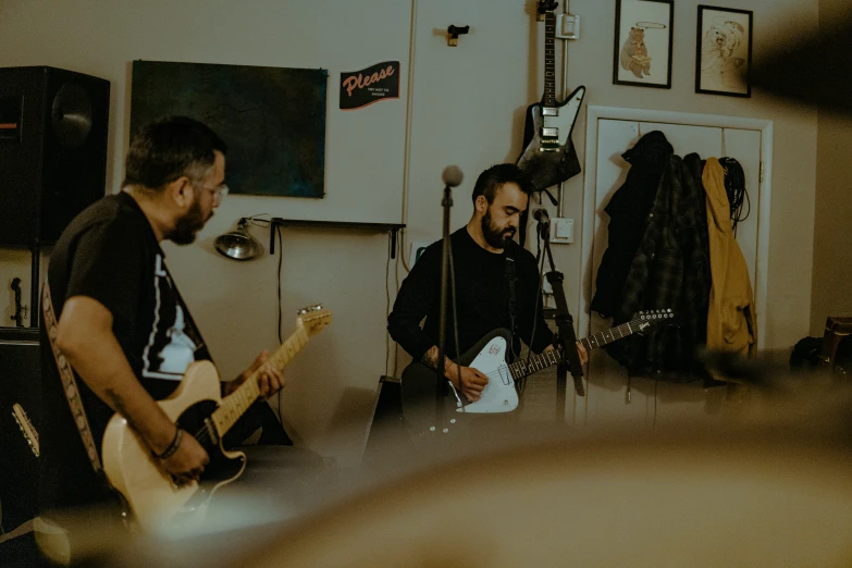 two men sitting down together playing guitars