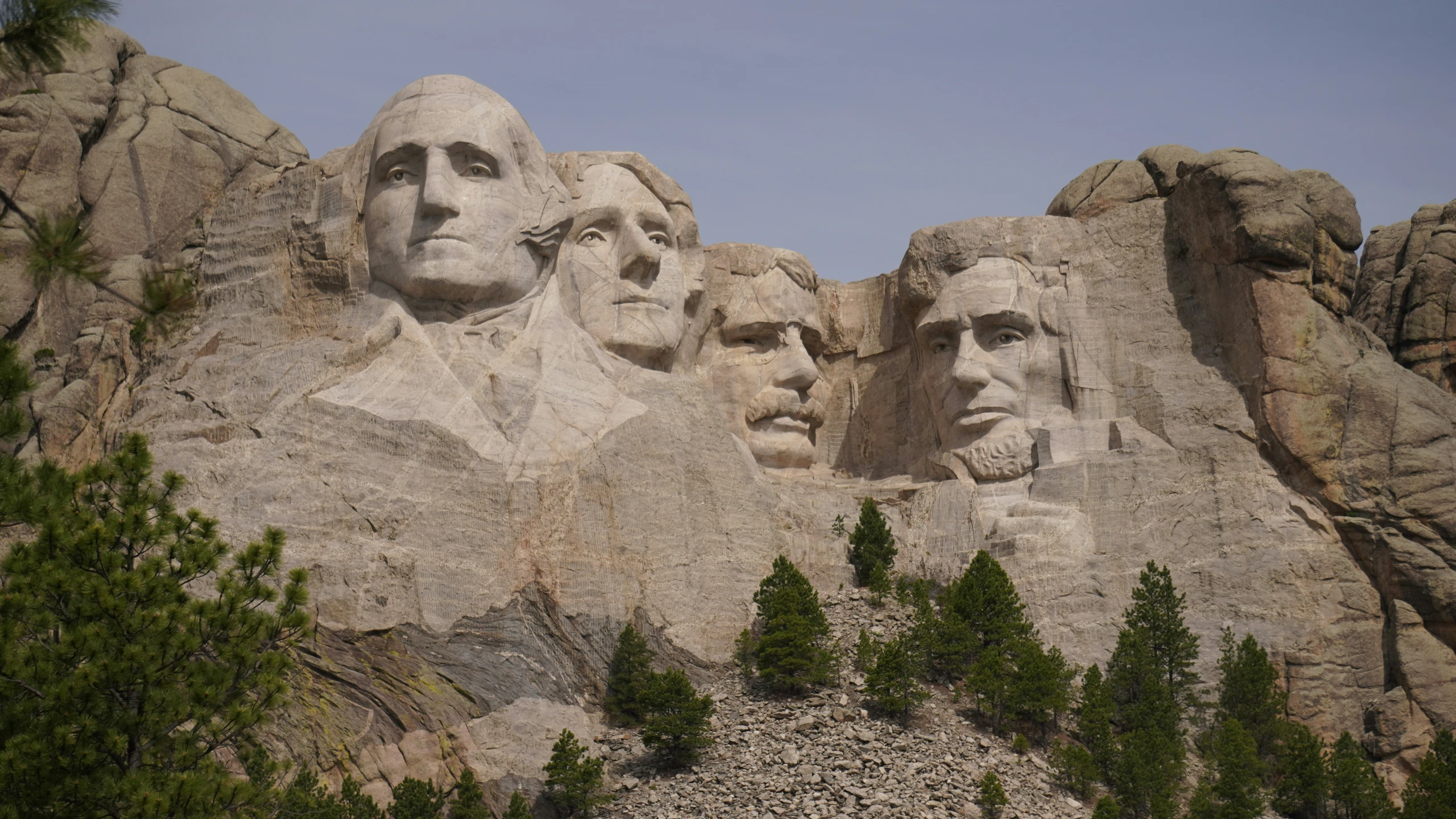 some huge rocks and trees with carved faces