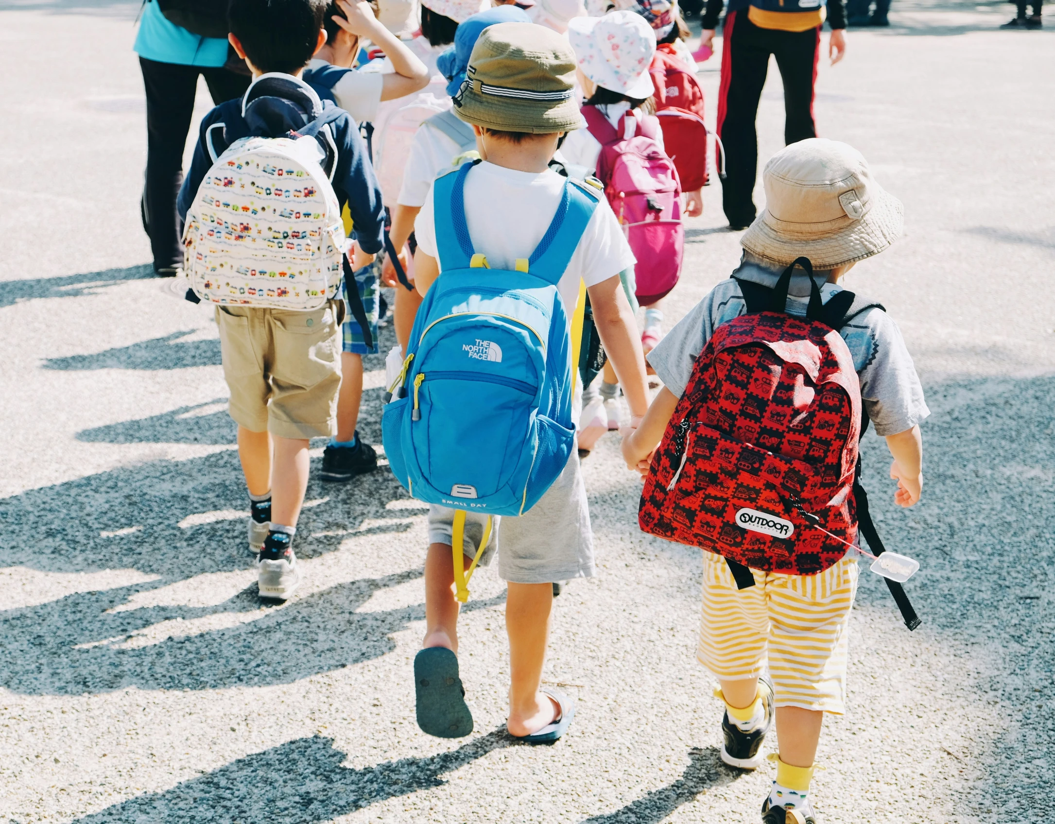 children walking together holding hands and carrying backpacks