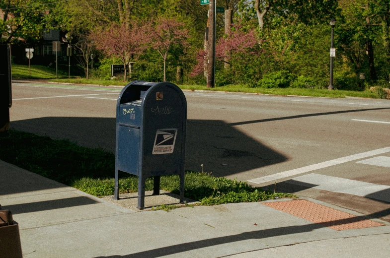 an empty black mail box on a sidewalk