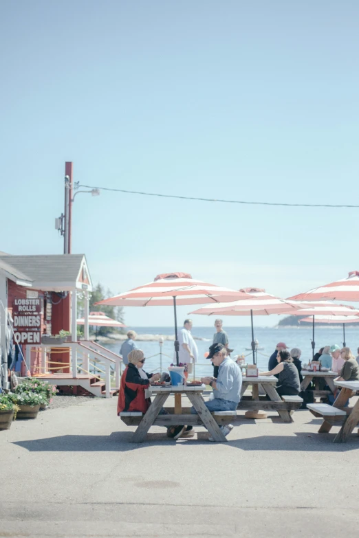 people sitting at picnic tables on the beach