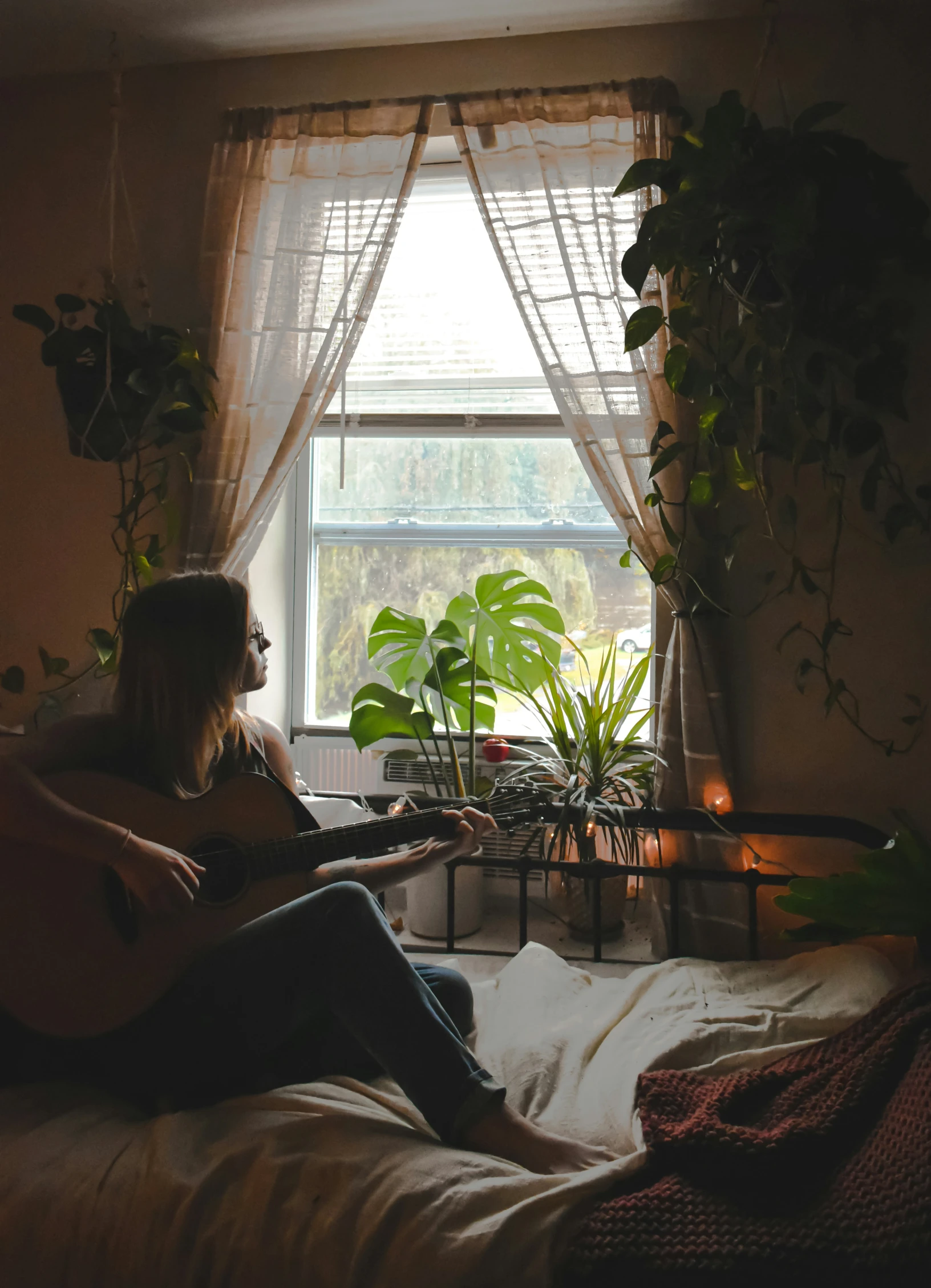 a woman sitting on top of a bed playing a guitar