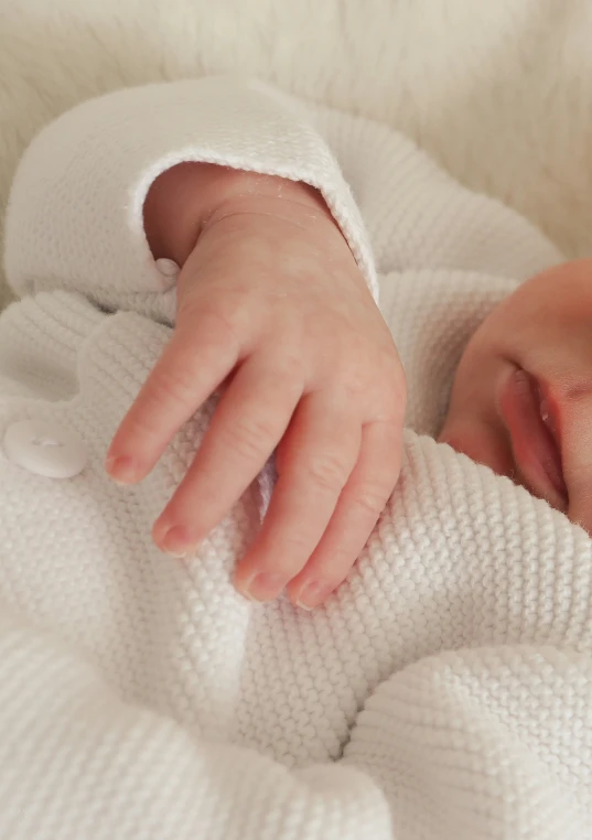 a baby wrapped in a white blanket looks into the camera