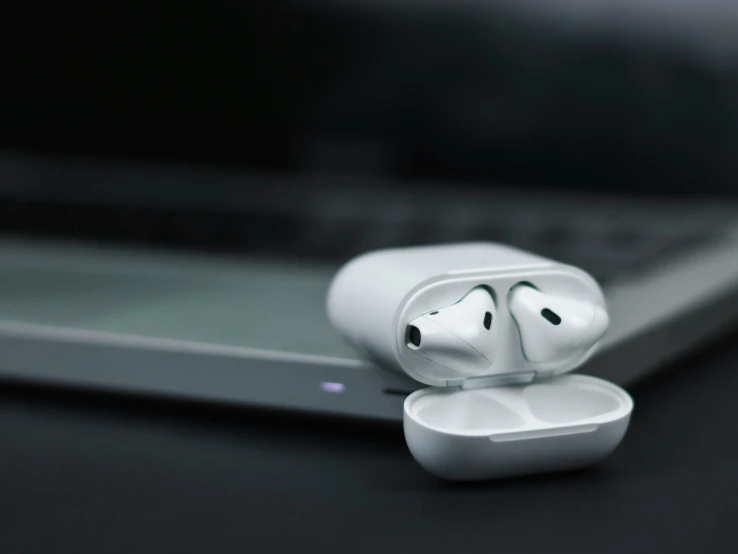 a white earpiece sitting next to an open laptop computer