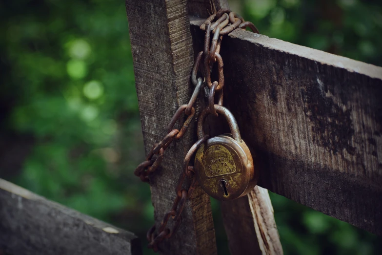 an old locked padlock attached to a wooden fence