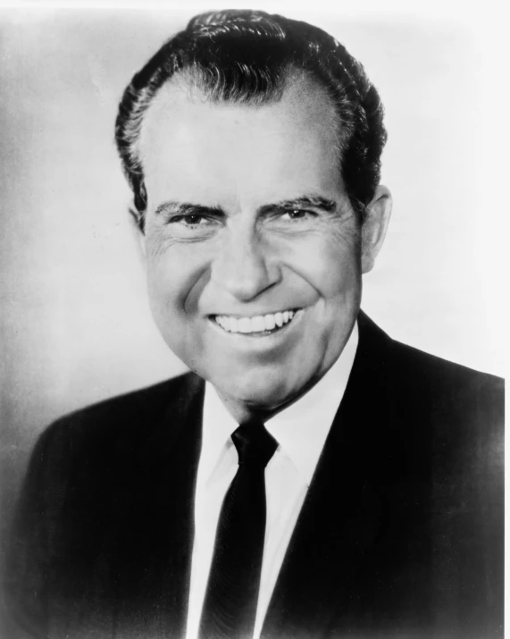 a smiling man with black hair wearing a suit