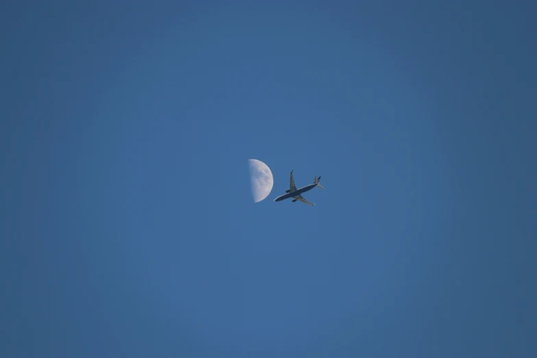 a plane is flying in the air with a half moon