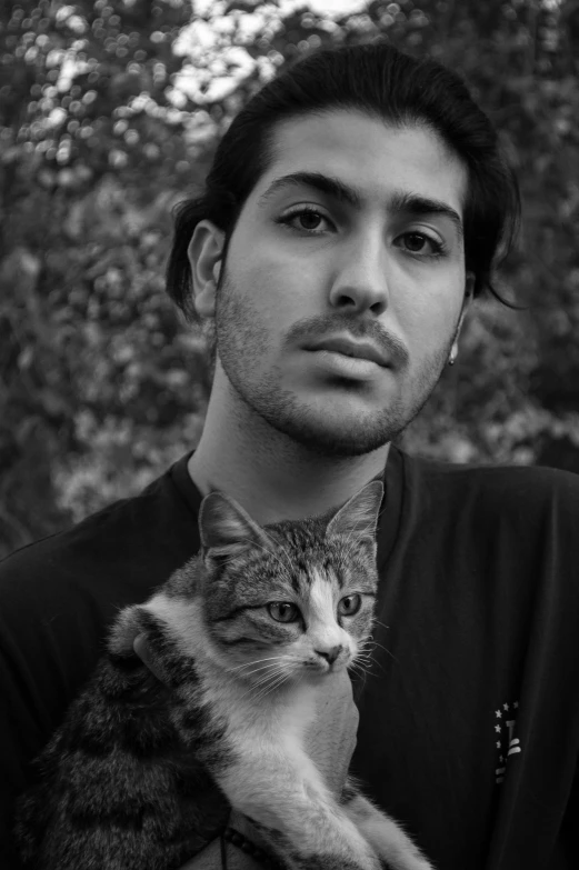 a black and white image of a young man holding a cat