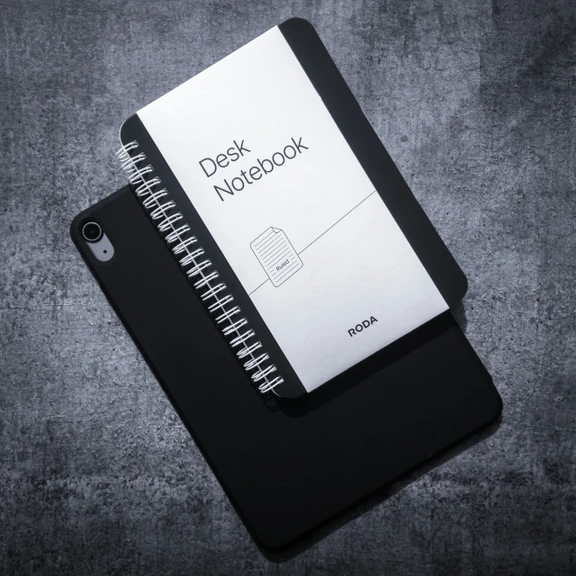 a black notebook with an apple sitting on it