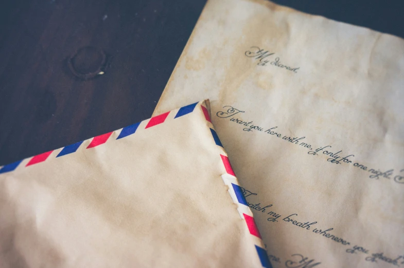 two envelopes with paper and a red blue and white ribbon are laying on the table