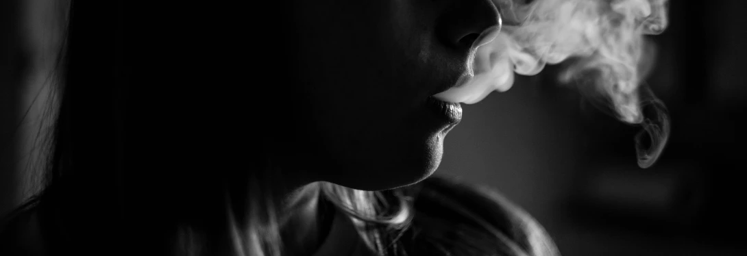 a person wearing glasses smokes a cigarette