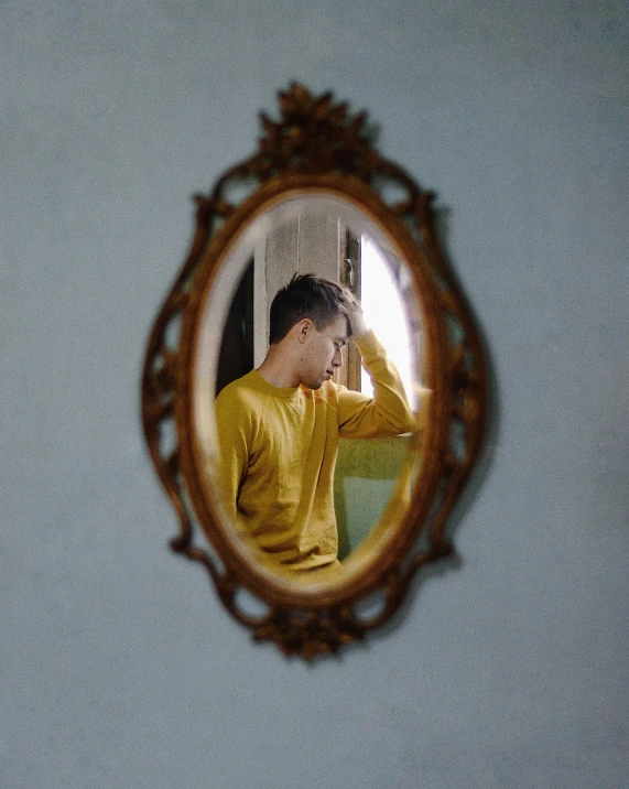 a reflection in the mirror of a boy sitting alone