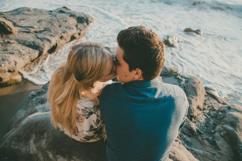 a couple of people sitting on rocks in the sand