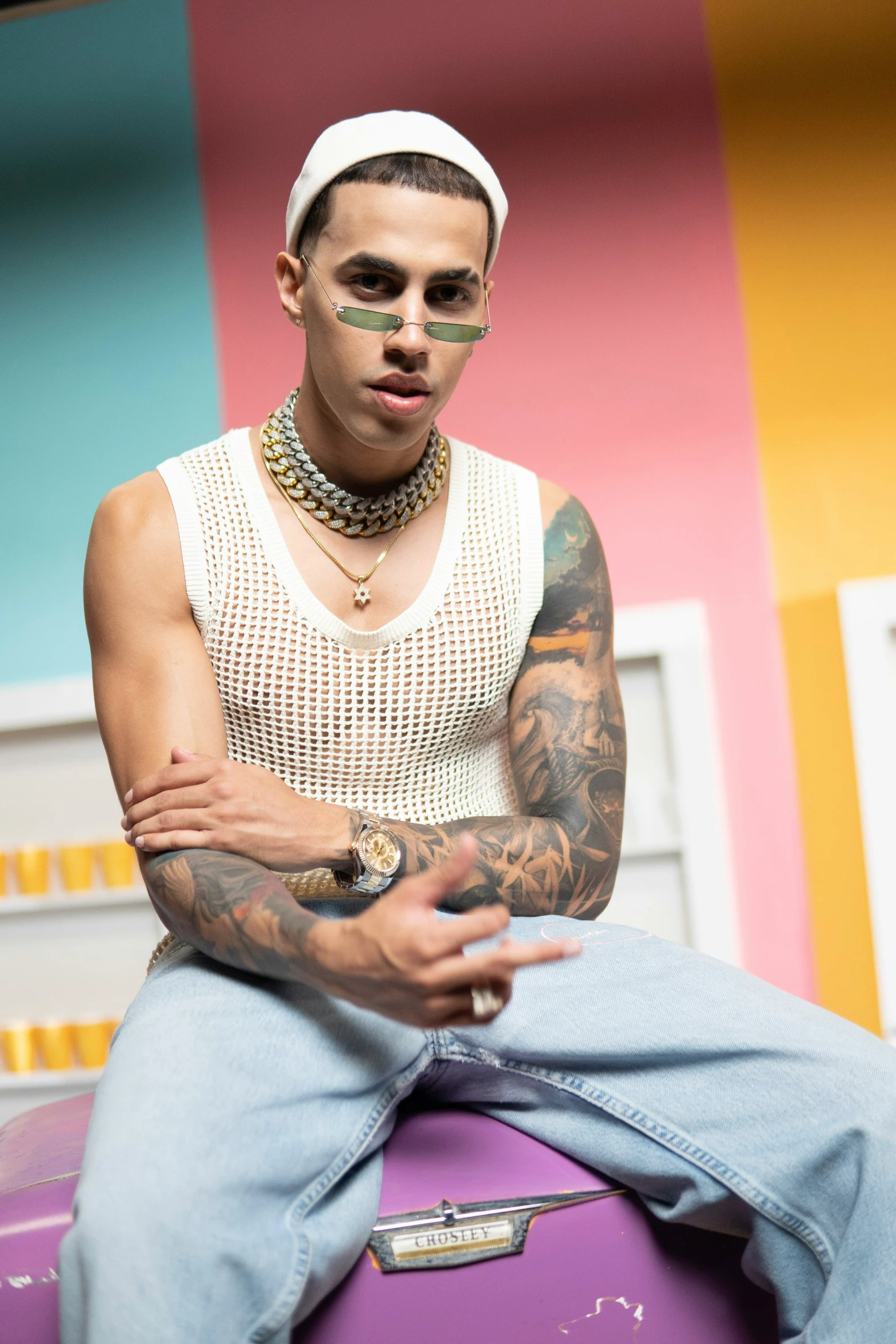 a man with tattoos sits on a luggage bag