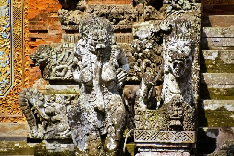 some statues next to some steps in front of a wall