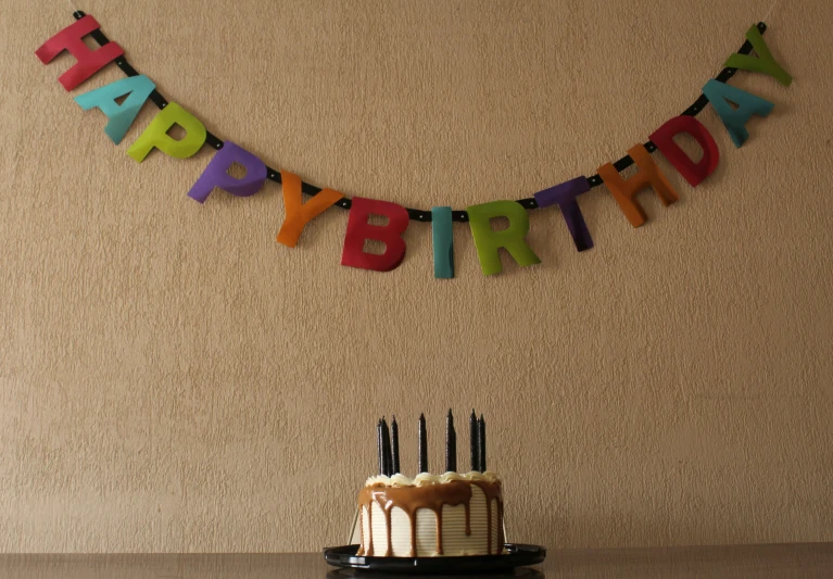 a birthday cake with candles and decorations hanging from the wall