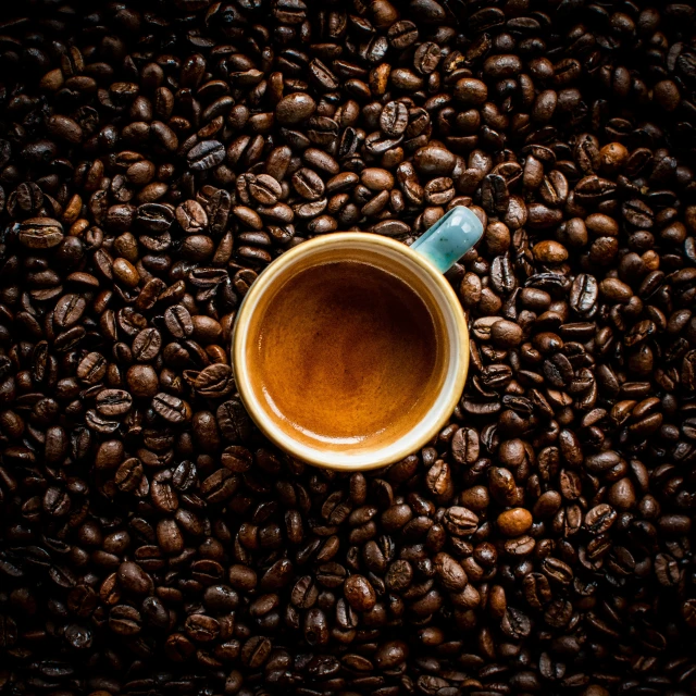 a coffee cup is sitting on the ground surrounded by coffee beans