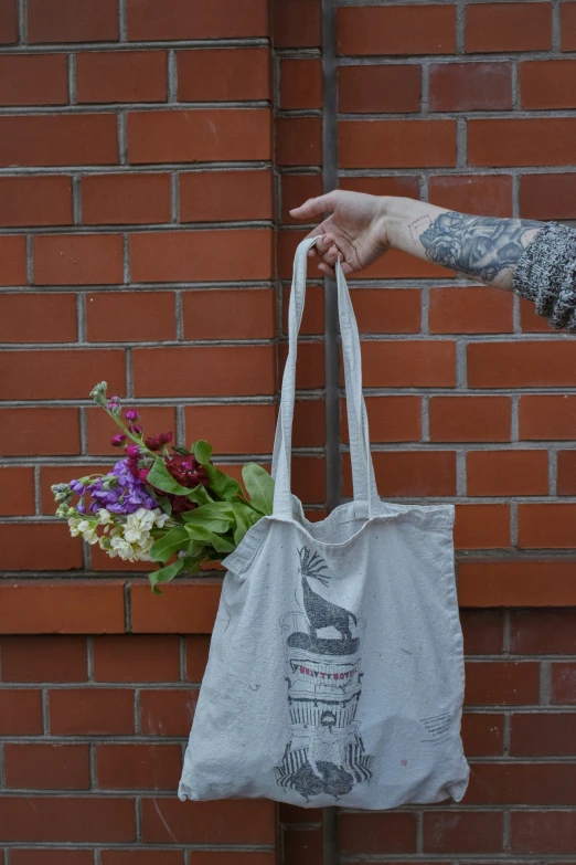 a hand holding a reusable bag near a wall