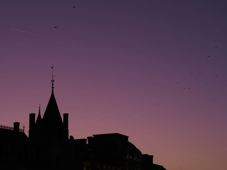 an old building with steeple silhouetted against the purple sunset