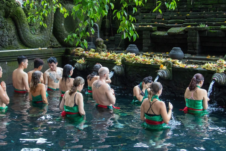 many people in the water are gathered at the edge of a waterfall