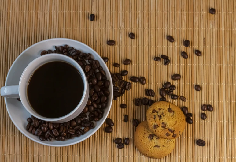 a cup of coffee next to two cookies