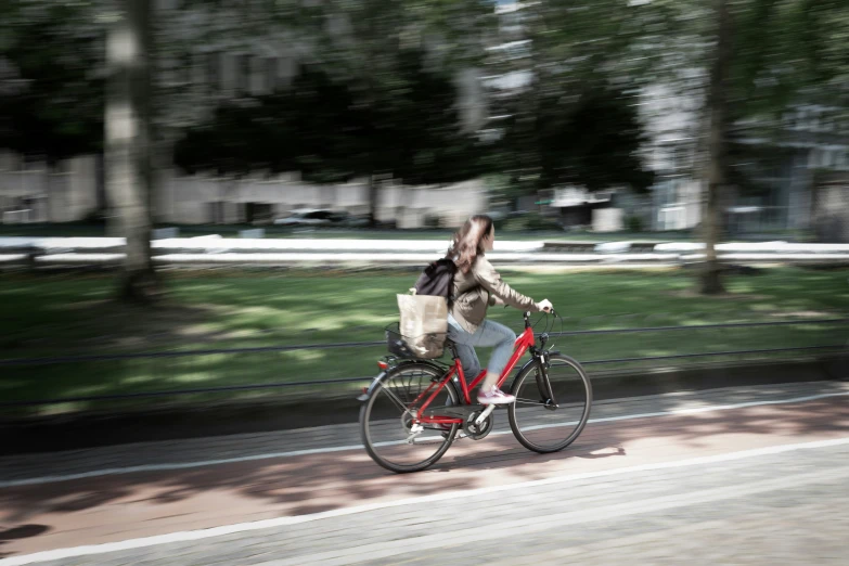 a woman riding a bicycle next to a park with lots of grass