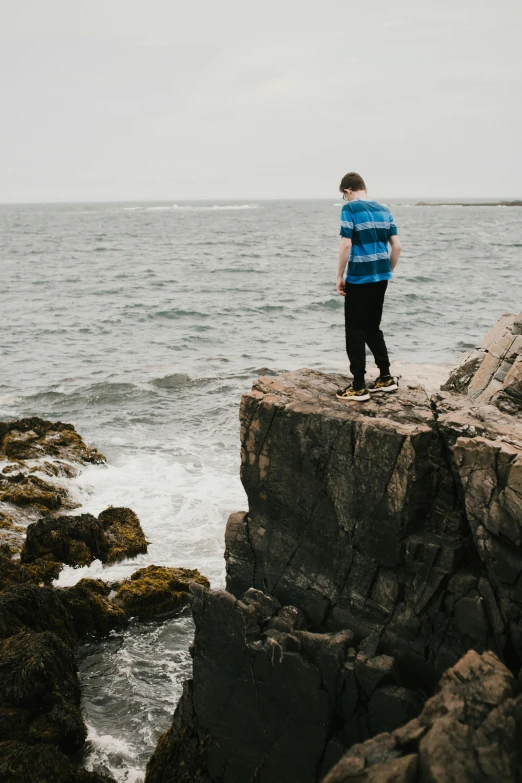 a man stands on the edge of a rock formation on a windy day