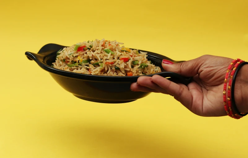 someone holding up a bowl with rice and vegetable