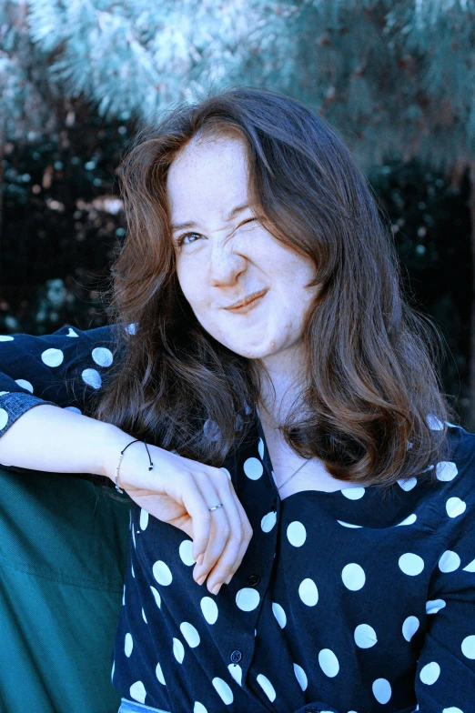 a woman with polka dots on her shirt looking straight ahead