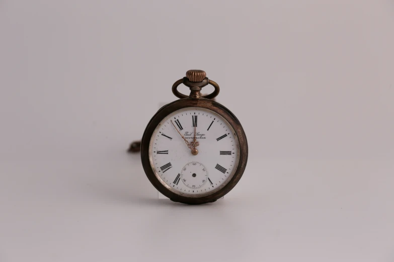 an old brown pocket watch with roman numerals and a gold face