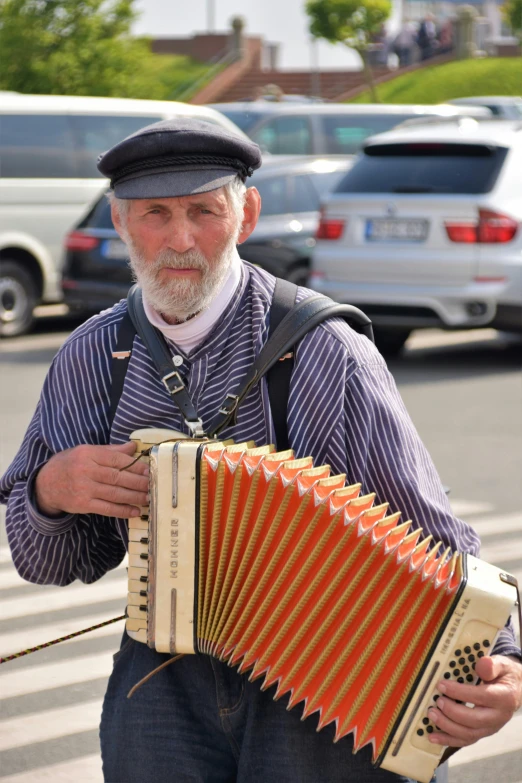 the man is playing the accordion in front of parked cars
