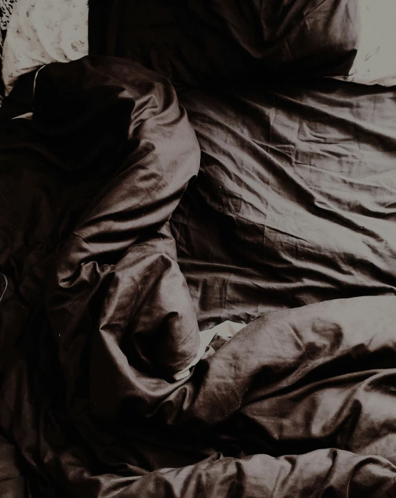 a person is sleeping in a bed covered with a black blanket