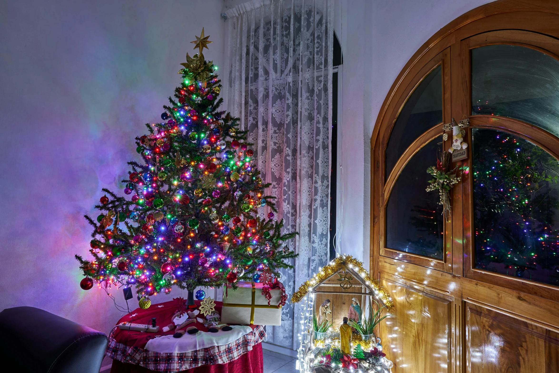 a brightly lit christmas tree next to a couch