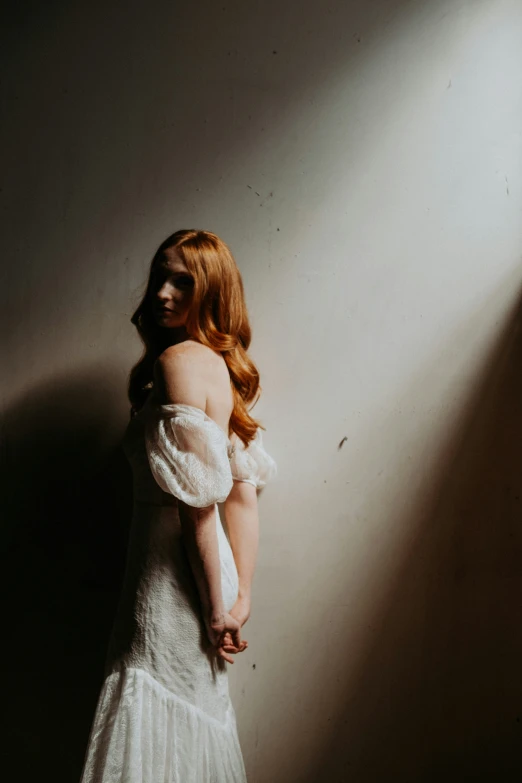 red headed woman standing in white dress with light shining through her eyes