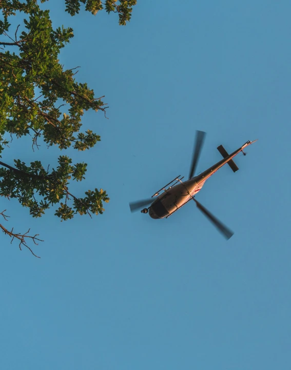 helicopter flying through the sky above some green trees