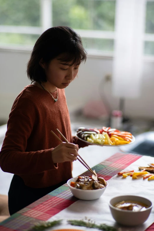 an asian woman with chopsticks is eating some food