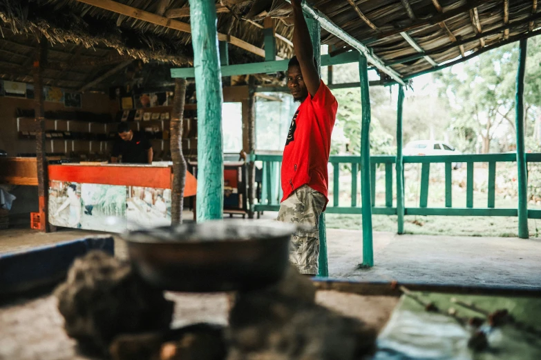 a man wearing camouflage clothing standing in front of a hut