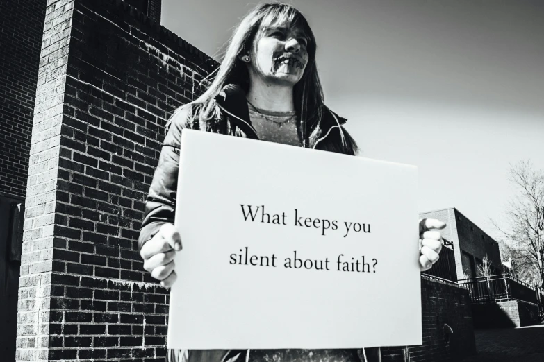 a girl holding up a sign that says what stops you silent about fail