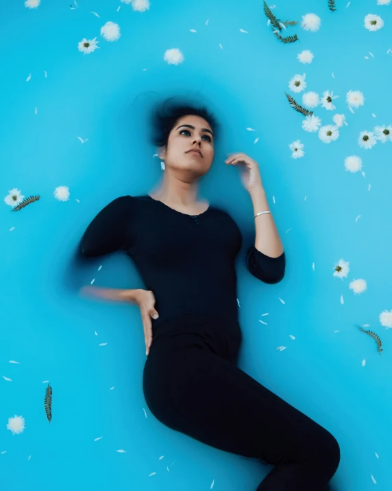 woman laying down on blue surface wearing all black