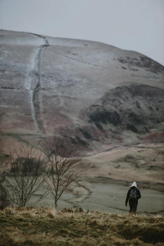 a lone person stands in front of a mountain