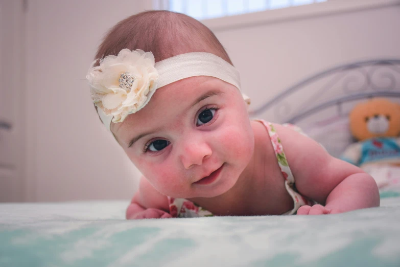 a baby laying on its back with a headband around her neck