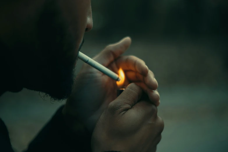 a man holding a lit cigarette looking down at it
