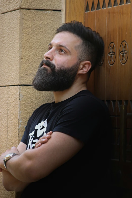 a man with a beard is leaning against a wall