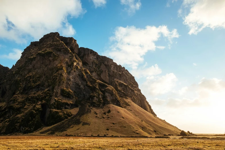 a tall mountain with some green grass